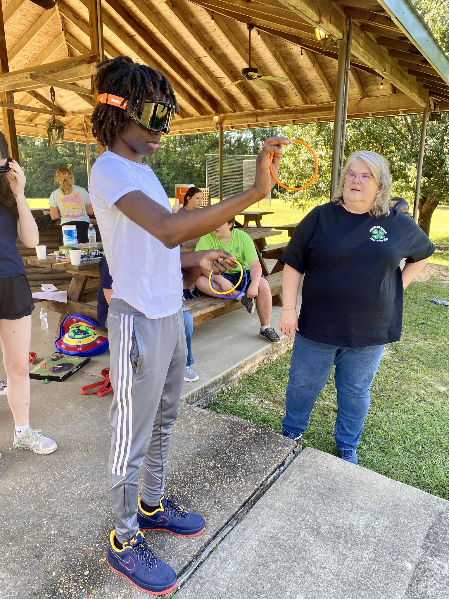 A boy wearing dark goggles and holding a tossing ring.